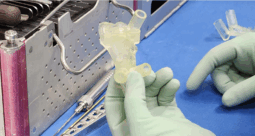 A gloved hand holding a 3D-printed implant