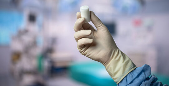 Gloved hand in the O.R. holding Miach's BEAR Implant.