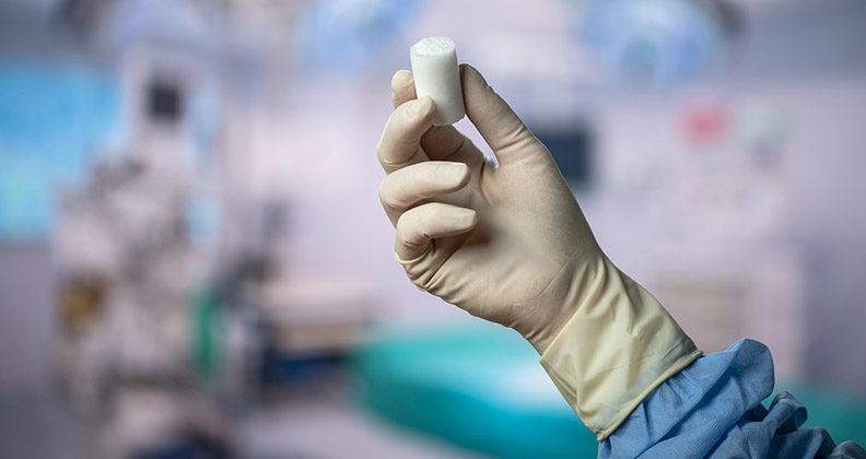 Gloved hand in the O.R. holding Miach's BEAR Implant.