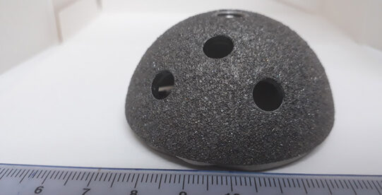 Acetabular cup implant with a ruler along the bottom of the image