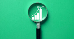 Magnified glass focused on the word quality against a light green background