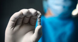 Close up of a gloved surgeon hand holding Spinal Simplicity's Patriot-SI implant