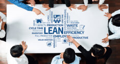 Overhead shot of a business team leaning over a table filled with product development terms in a word bubble