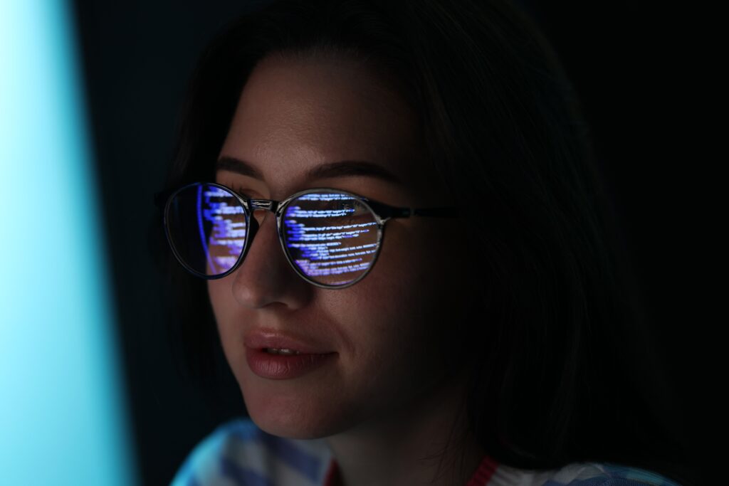 Woman looking at computer with data reflected on her glasses