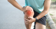 Jogger bending down to hold a sore knee