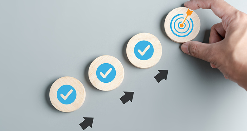 Checkmarks in wooden circles ascending to a target graphic held by a hand