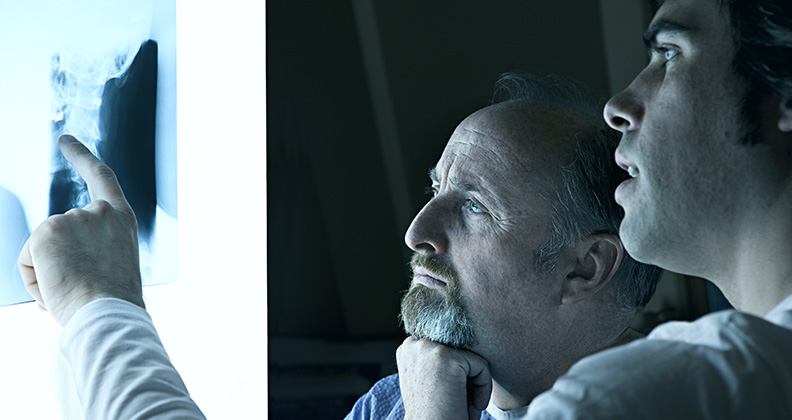 guy with hand to chin looking at spine x-ray