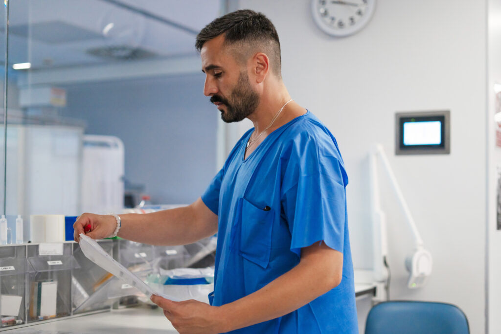 Man in blue scrubs looking at a sheet of paper