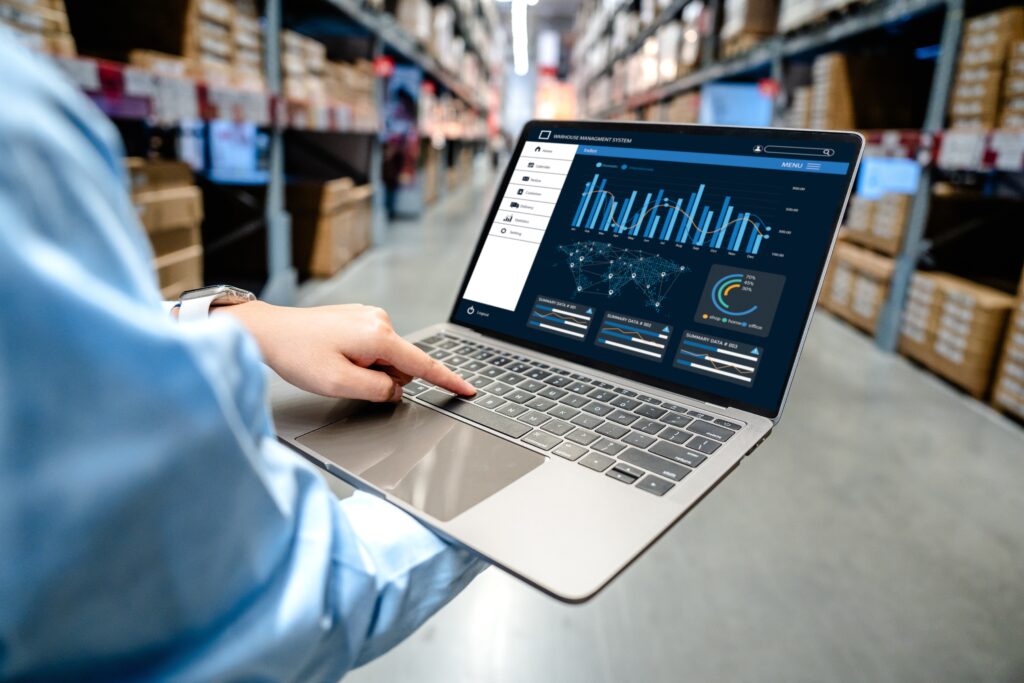 A worker holding an open laptop in a warehouse